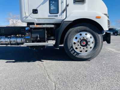 Mack MD6 cab and front wheel area showing wheel, tire, steps, and fuel/air lines; side view of truck with chassis components visible.