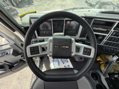 Mack MD6 steering wheel and dashboard inside cab showing steering wheel with Mack logo, gauge cluster, center display, and control panels.