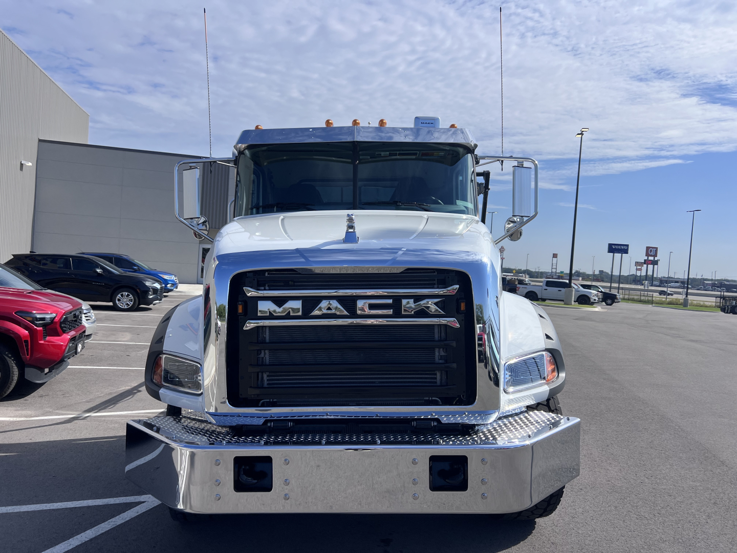 Mack GR64B truck front view showing chrome grille with MACK emblem, large bumper with diamond plate, and side mirrors.