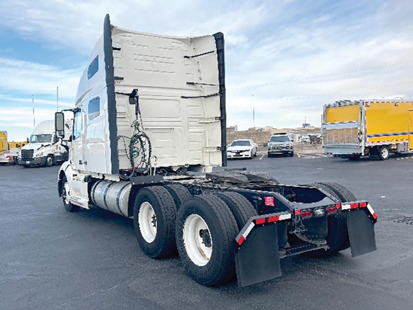 Truck rear view with sleeper cab and dual rear axles showing fifth wheel and mud flaps.