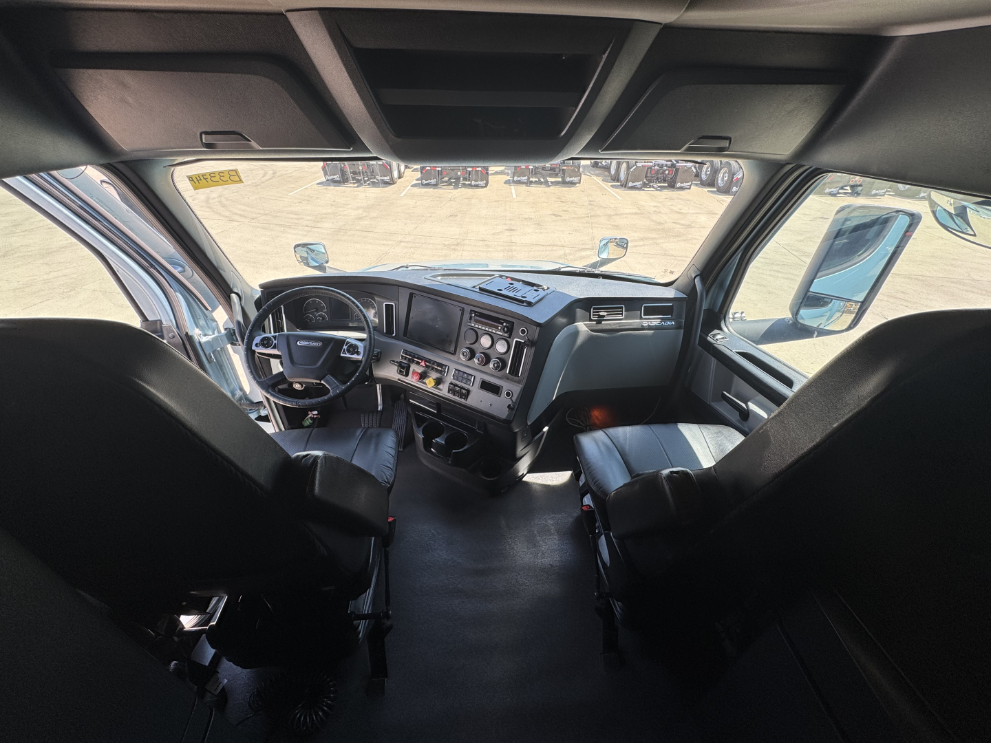 Truck cab interior view from driver seat in Freightliner Cascadia 126 sleeper showing dashboard gauges and steering wheel.