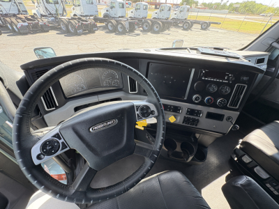 Freightliner Cascadia 126 cab interior showing steering wheel, dashboard with large digital display, gauges, and control panel.