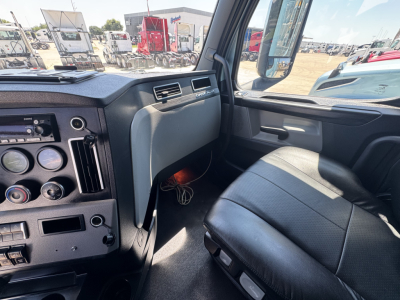 Freightliner Cascadia 126 cab interior view showing dashboard gauges, steering wheel, passenger seat, and side window.