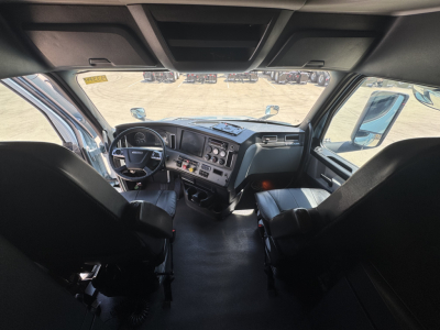 Truck cab interior view from driver seat in Freightliner Cascadia 126 sleeper showing dashboard gauges and steering wheel.