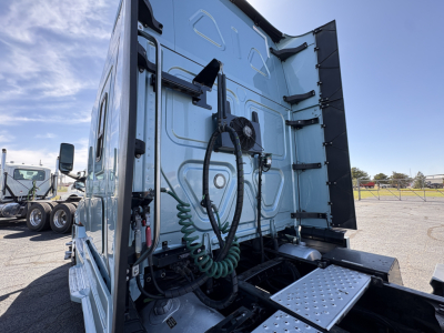 Freightliner Cascadia 126 sleeper cab rear/side view showing exterior panels and hydraulic hoses, green coiled air line, rear steps, and door hinges.
