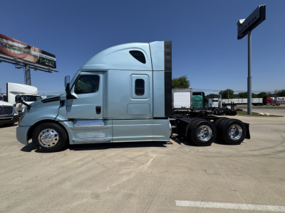 Freightliner Cascadia 126 sleeper cab tractor in blue-gray profile view with triple rear axles visible and no trailer.