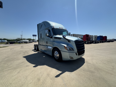 Freightliner Cascadia 126 sleeper cab truck parked in lot, front three-quarter view, silver exterior, multiple trailers in background.