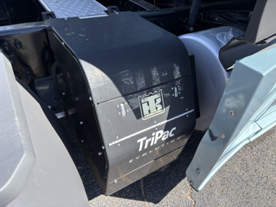 Trapped air intake or battery box labeled Tripac Evolution under the cab of a Freightliner Cascadia 126; black metal housing with Tripac Evolution logo.