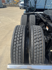 Truck rear dual tires and chassis viewed from side; no legible text visible on components in image.