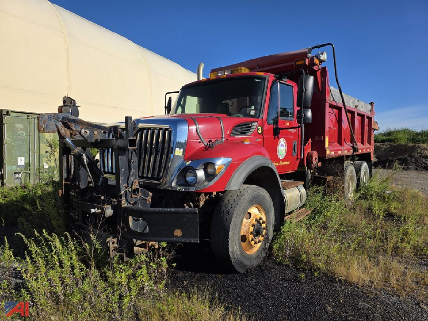 Red 2009 International WorkStar 7500 dump truck with sander body, front bumper guard, black honeycomb grille, large tires, and side cab mirrors. Vehicle shows worn front fender and badge details.