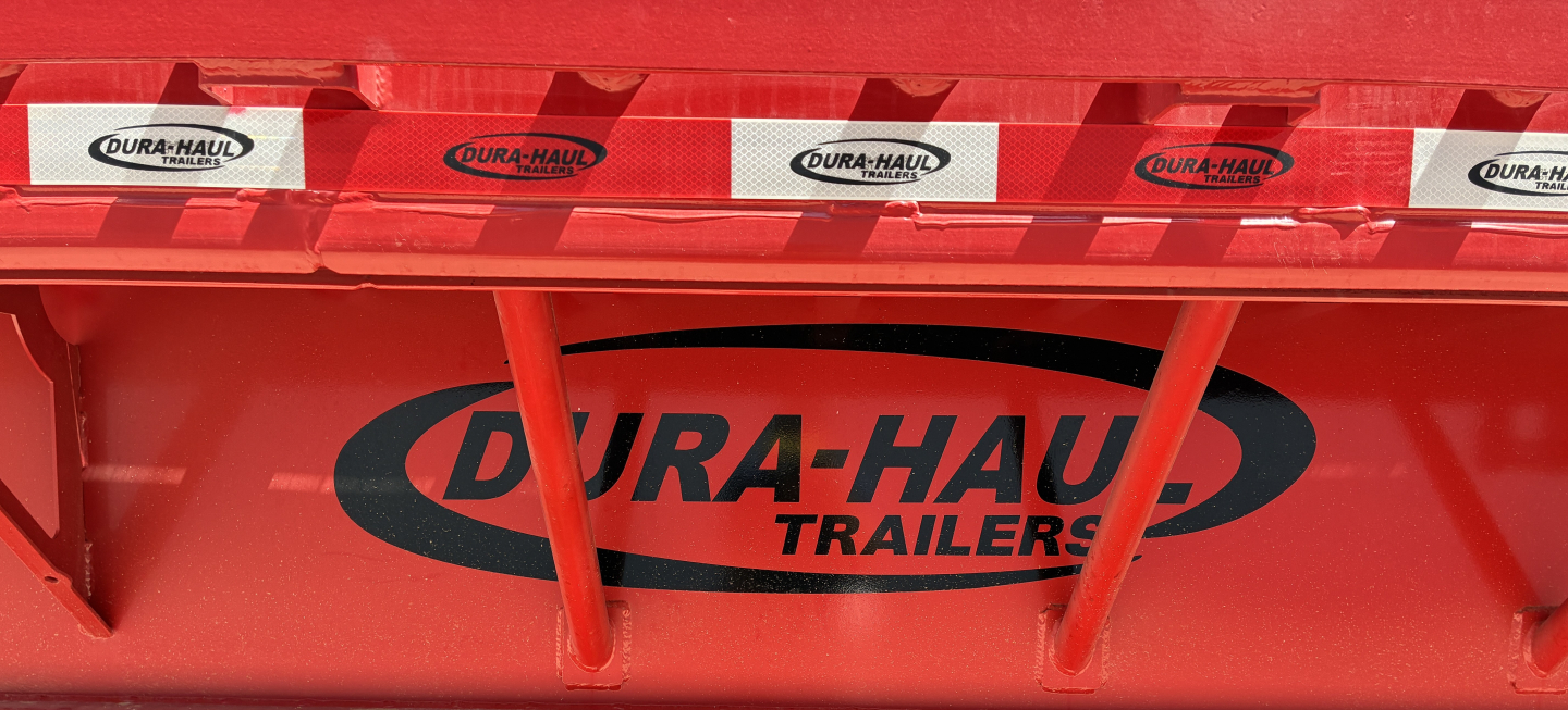 Red Dura-Haul trailer side with 'DURA-HAUL TRAILERS' logo and red reflective tape showing repeated Dura-Haul branding.