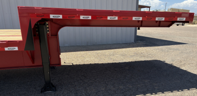 Red 2026 Dura Haul drop deck trailer leg and frame close-up showing attached support leg and underside of deck with branding stickers.