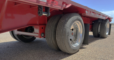 Trailer axle and wheel area of a red 2026 Dura Haul drop deck trailer showing dual rear wheels and undercarriage.
