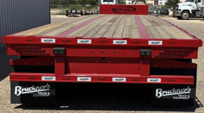 Flatbed trailer with red frame and wooden deck, rear view showing Bruckner's Truck & Equipment mud flaps and Dura-Haul branding.