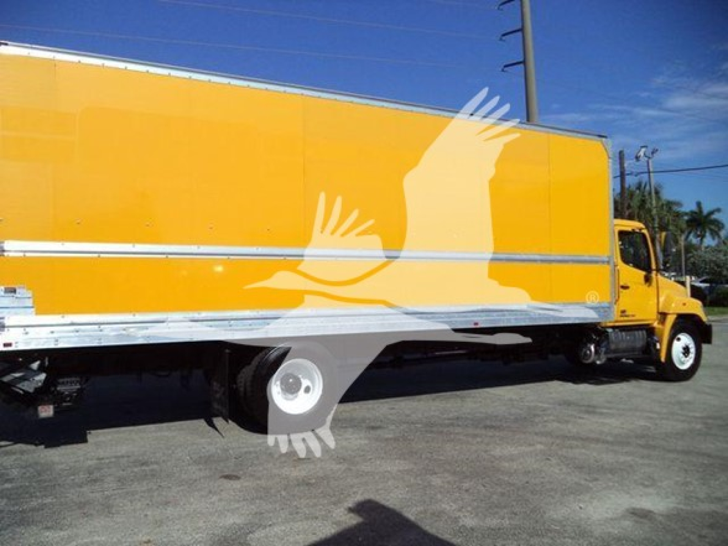 Box truck with yellow cargo body and white chassis viewed from mid-side profile showing Hino 268A box truck.