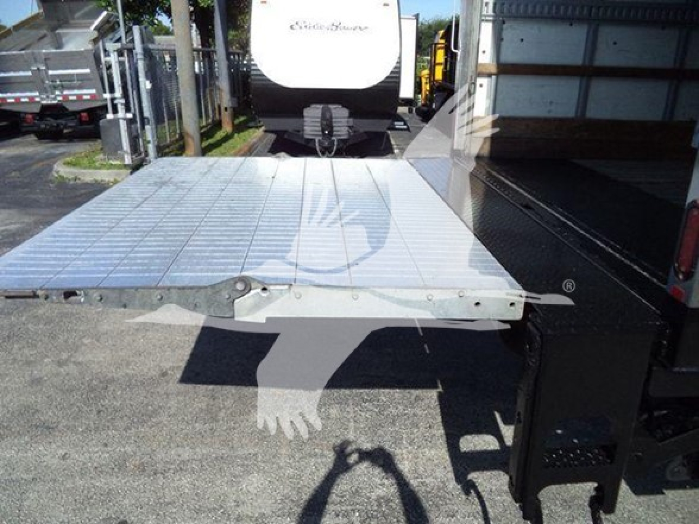 Flatbed truck part with metal diamond plate and hinge, rear platform view showing edge detail and mounting hardware.