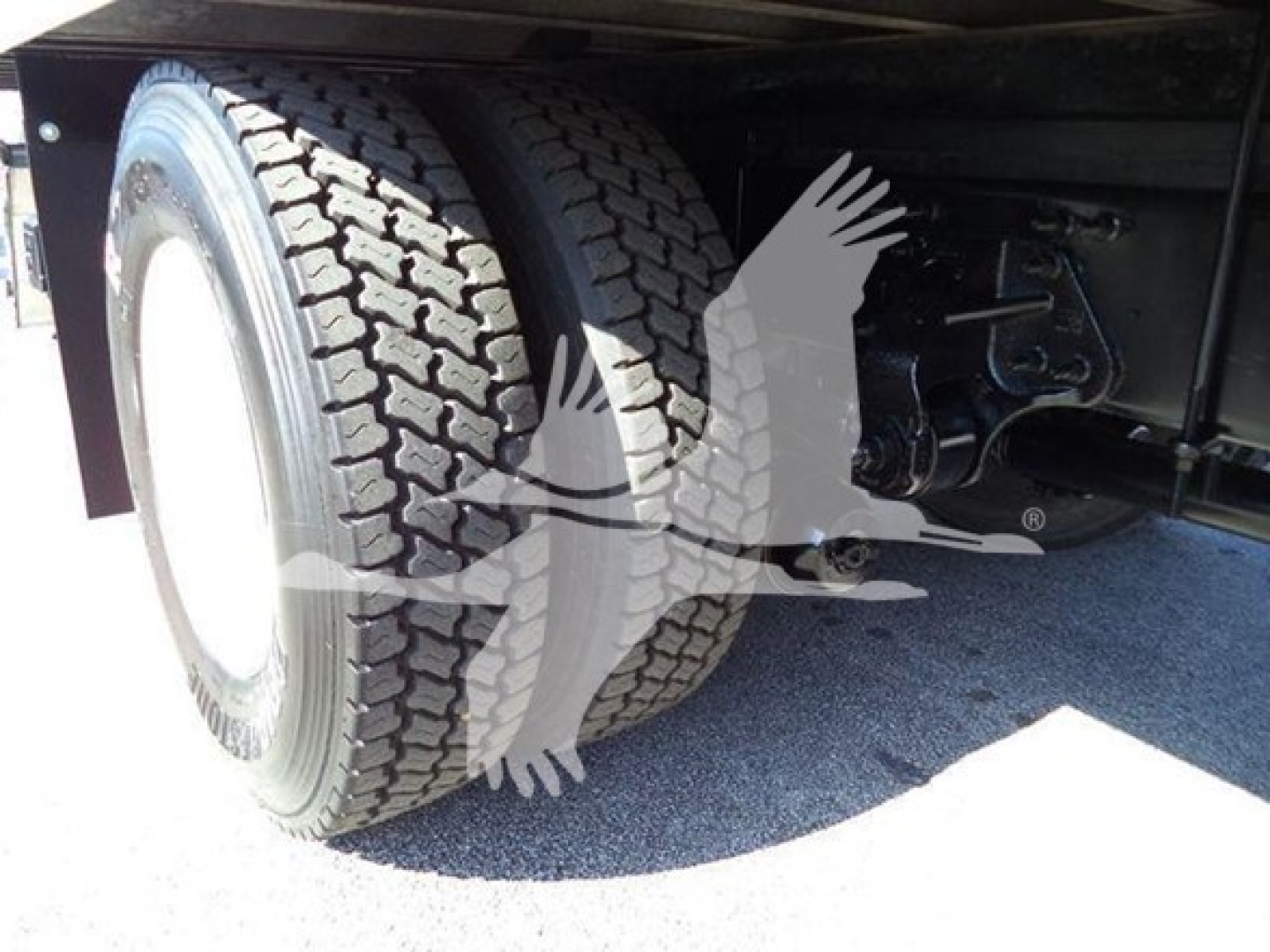 Truck rear wheel and axle area showing dual tires on a Hino 268A box truck trailer suspension and frame components.