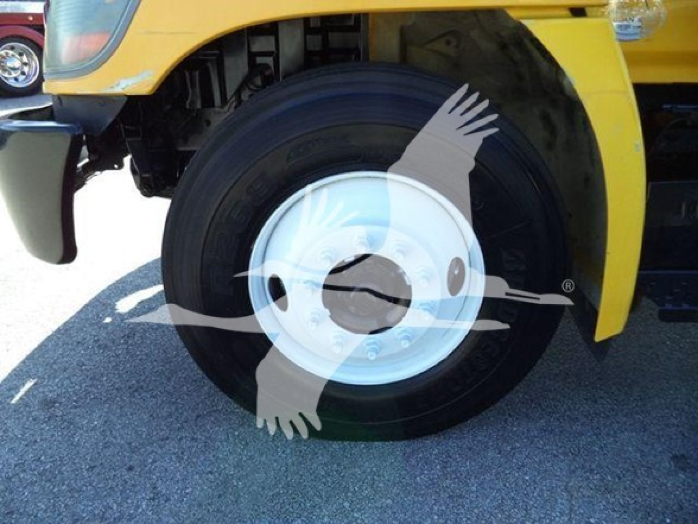 Hino 268A front wheel and fender area showing wheel and tire with white hubcap, yellow body panel, and partial chassis.