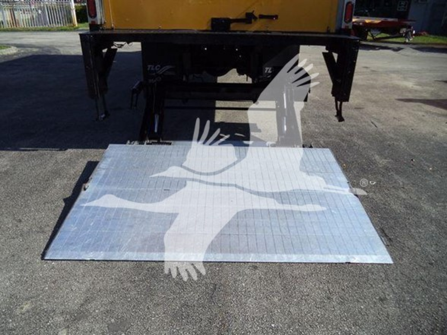 Hino 268A truck rear with lowered aluminum lift/step showing platform with bird logo overlay.