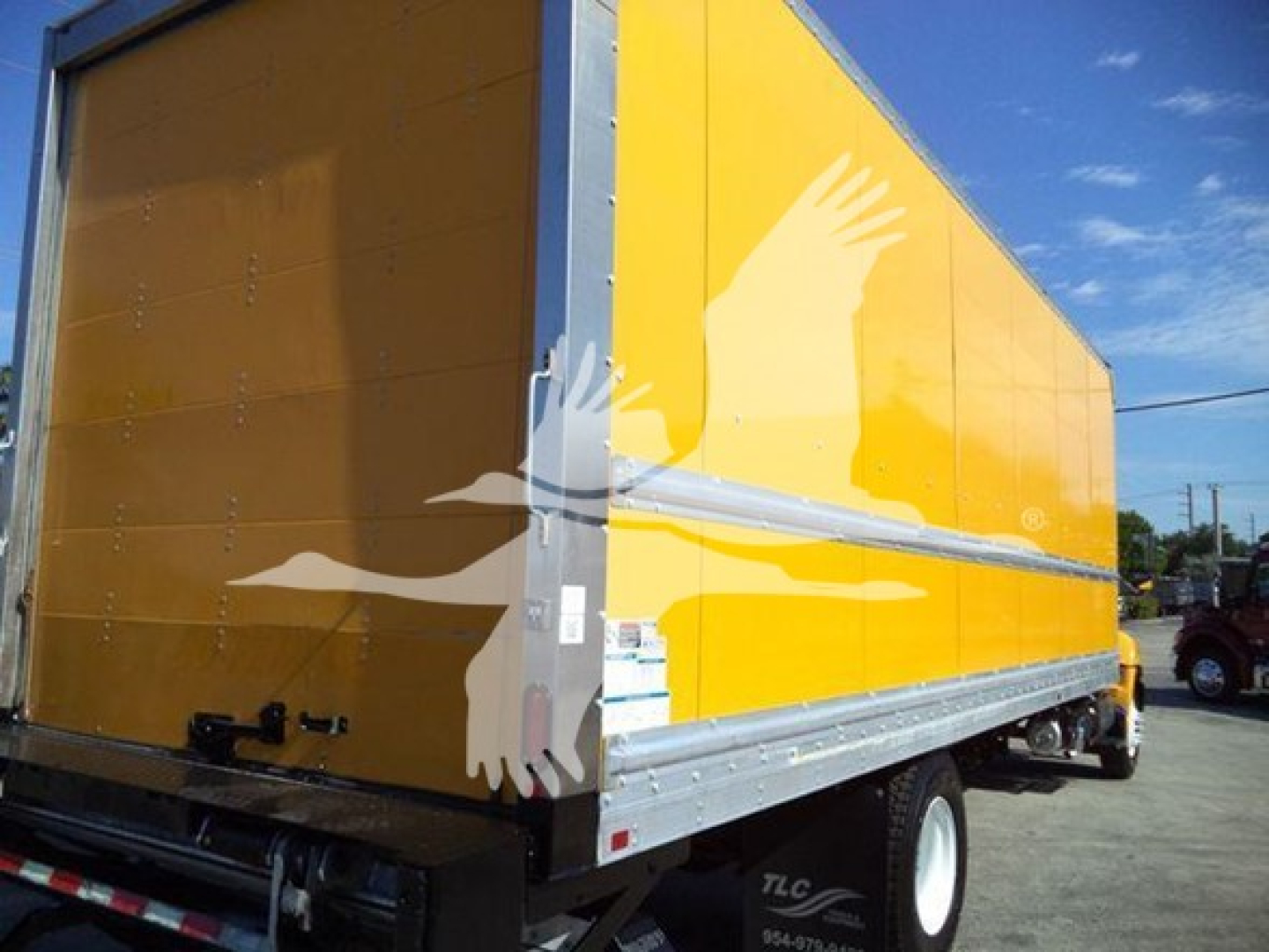 Truck cargo box rear left side showing yellow exterior with silver lower edge and wheel, Hino 268A truck.