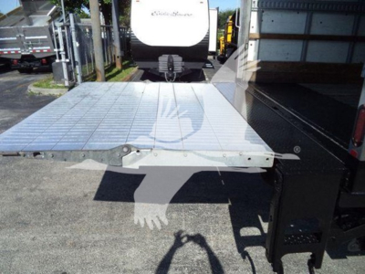 Flatbed truck part with metal diamond plate and hinge, rear platform view showing edge detail and mounting hardware.