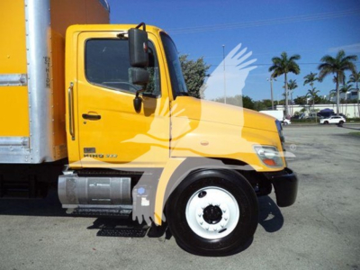 Truck hood and cab of a 2019 Hino 268A with yellow exterior, showing front wheel, side step, and part of the cargo box.
