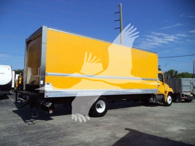 Truck cab and bright yellow box truck at a lot showing rear cargo area and side view
