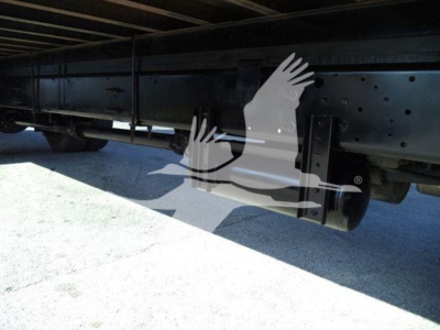 Underbody view of a box truck chassis showing a reinforced frame rail and leaf spring suspensions with a visible axle area.