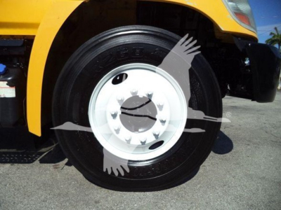 Wheel close-up showing black tire with white rim on yellow truck, hub-center with bolts visible.