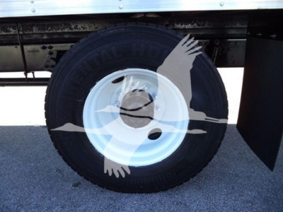 Wheel and tire of a Hino 268A box truck showing black tire and white steel rim with center hub cap.