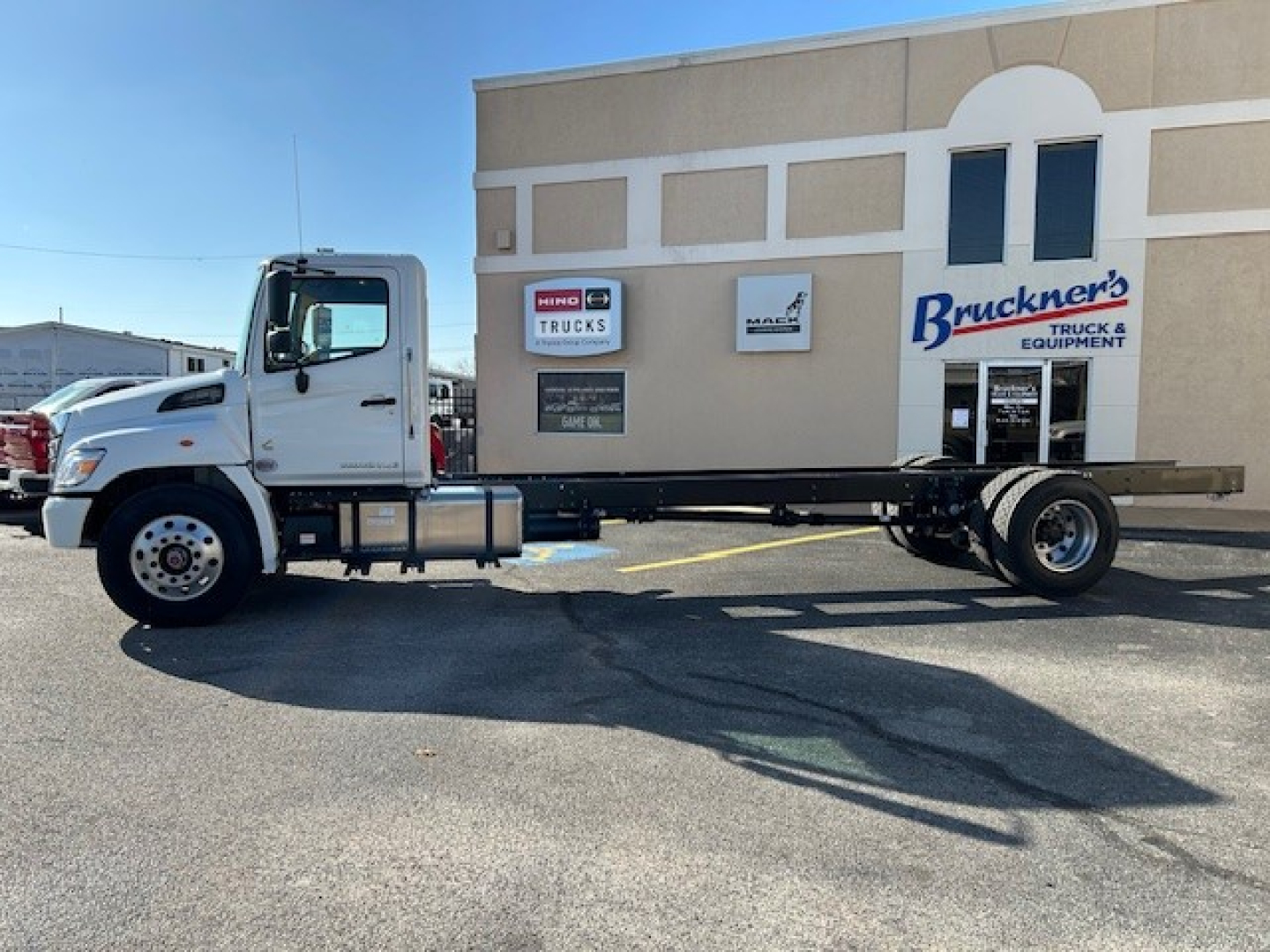Truck chassis in front of Brückner's Truck Equipment building showing Hino cab and chassis with flatbed-style frame.