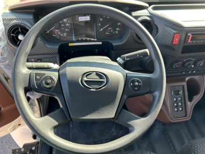 Steering wheel of a 2025 Hino L6 cab and chassis showing Hino emblem; dashboard and control stalks visible with instrument cluster and center console