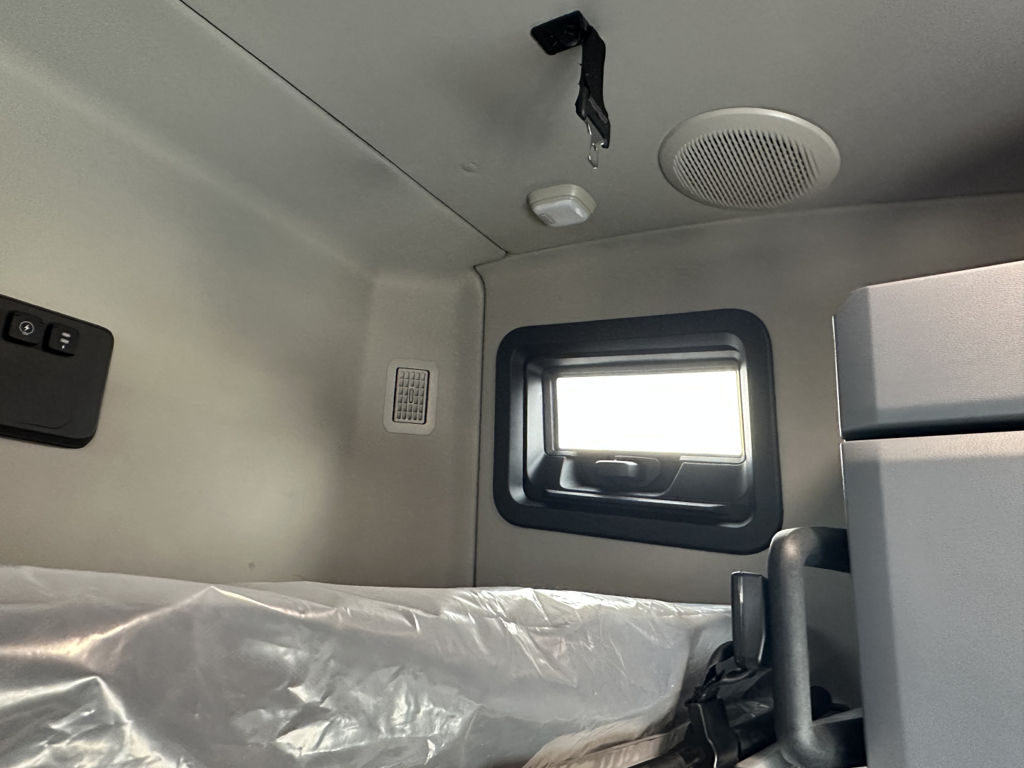Truck cab interior showing sleeper area with window, overhead console, and speaker grille.