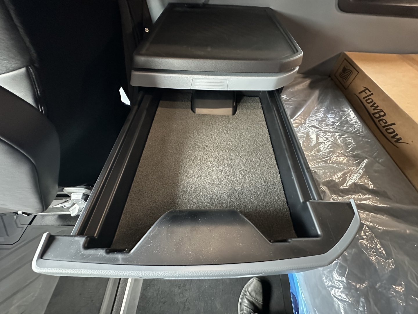 Truck interior center console open storage drawer with carpeted tray and side rails in cabin of 2026 Mack PR64T76H.