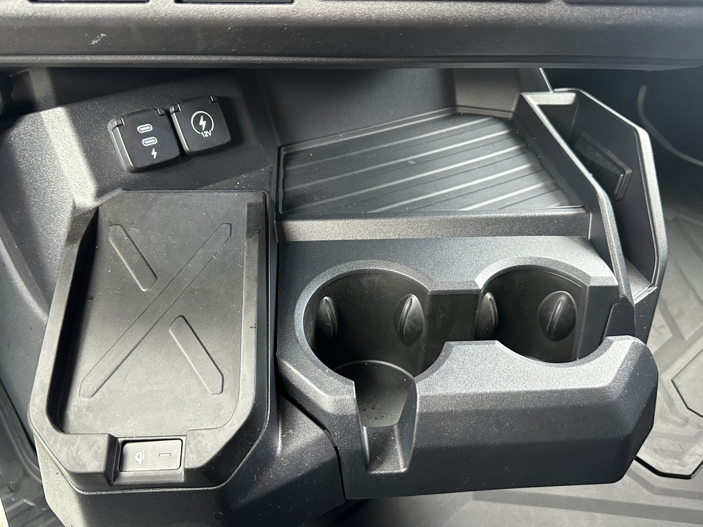 Truck interior showing console with cup holders and storage trays in a Mack PR64T76H cab.
