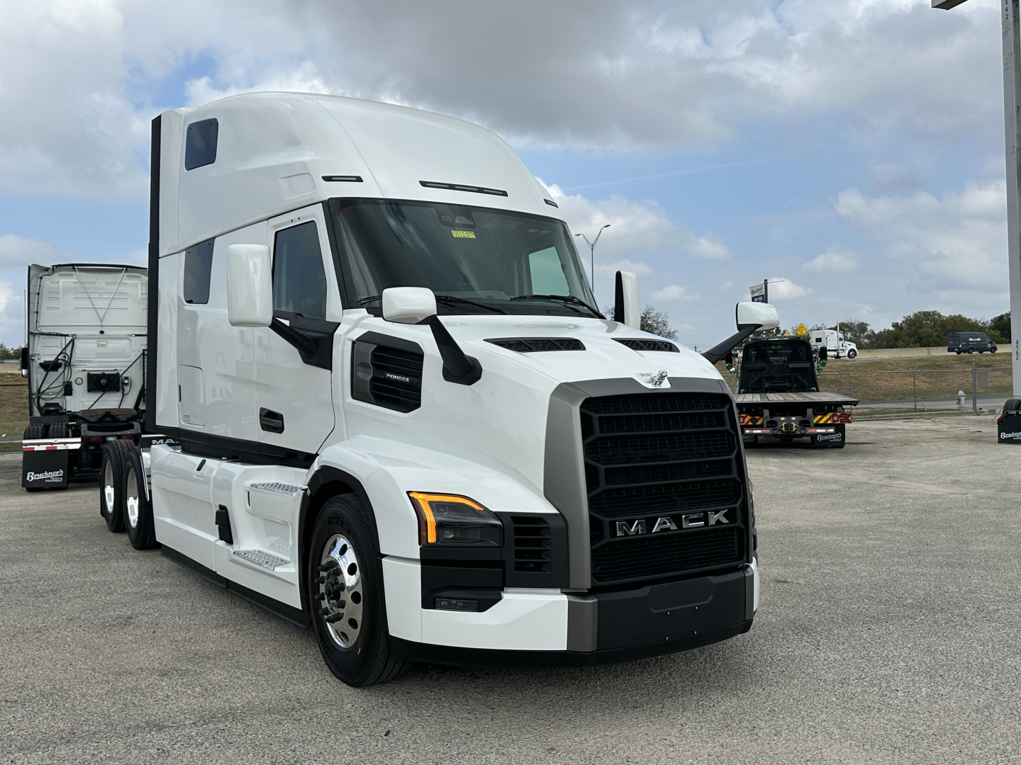 Mack PR64T76H conventional sleeper truck in white front-side view showing grille and cab details.