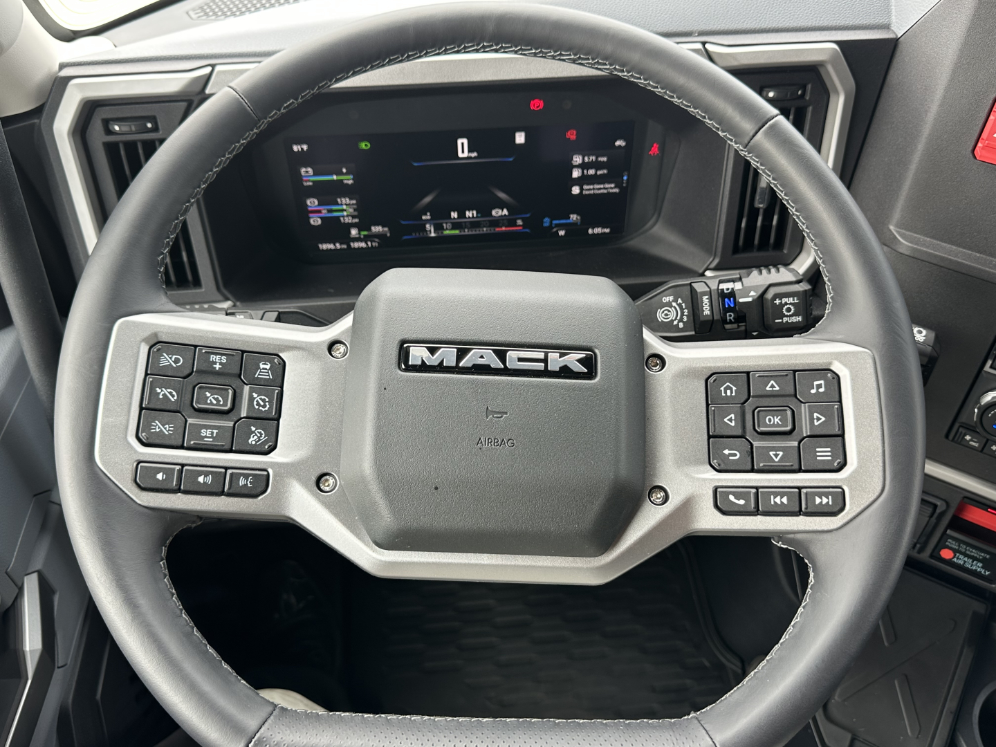 Mack PR64T76H steering wheel and dashboard cluster in cab showing steering wheel with Mack logo and digital instrument display.