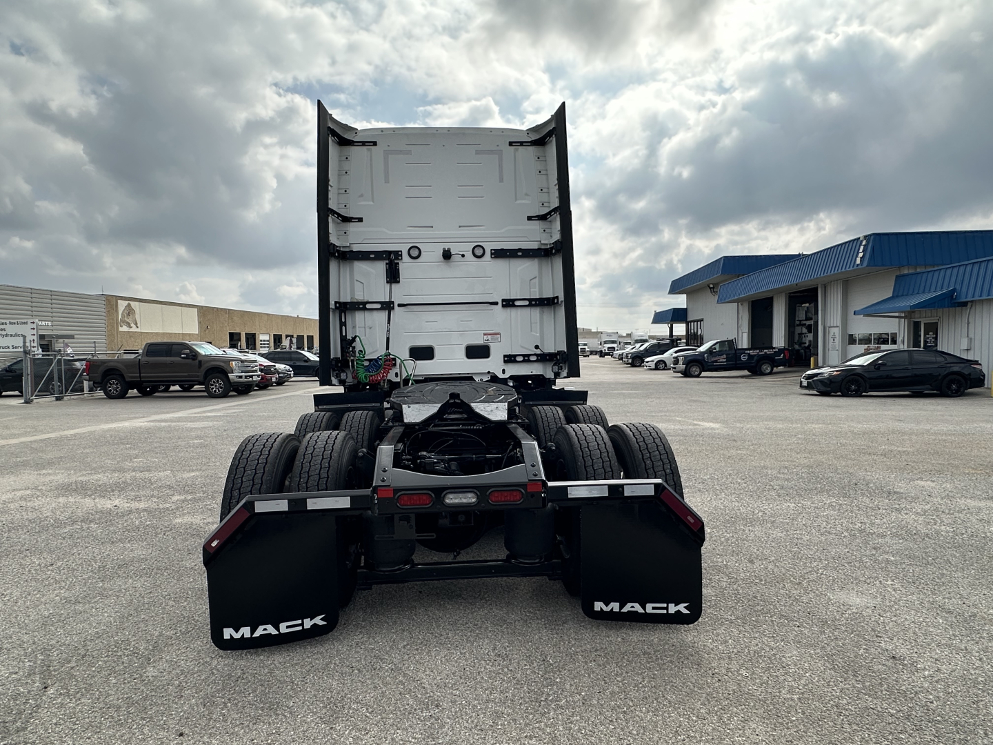 Truck chassis rear view showing fifth wheel, dual rear wheels, mud flaps labeled MACK, and fifth wheel area with air lines; semi-truck tractor without trailer.