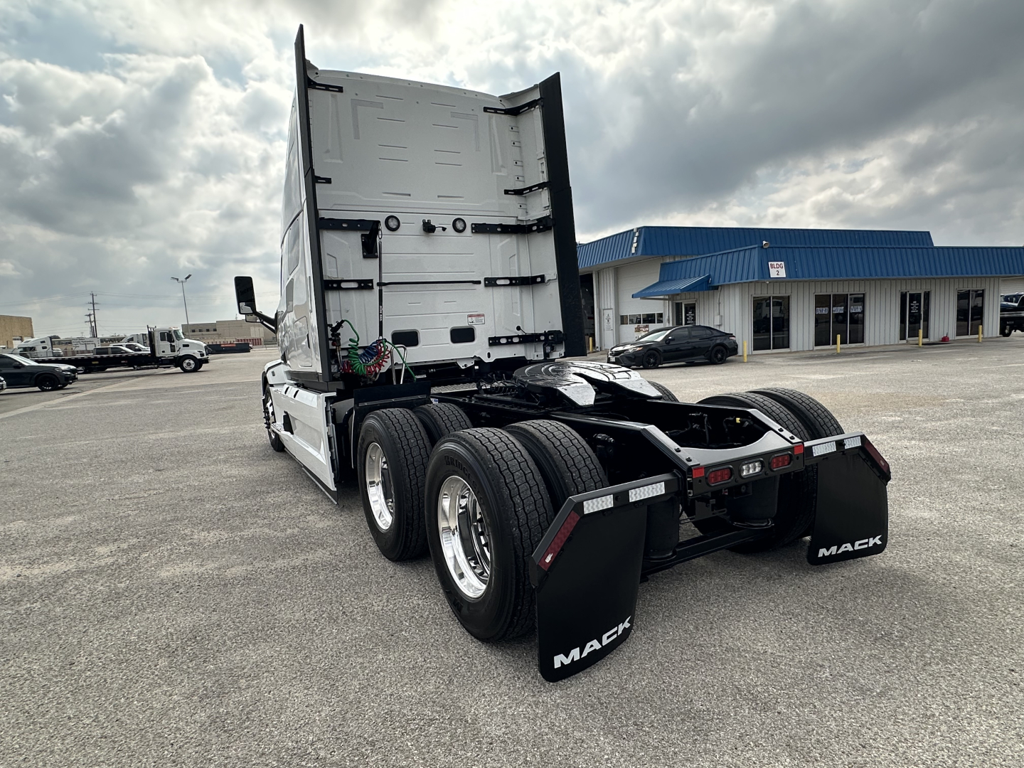 Truck tractor rear view showing dual rear axles and fifth wheel with mud flaps labeled MACK.