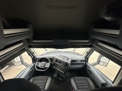 Interior cab view of a new 2026 Mack PR64T76H truck from the driver’s perspective, showing steering wheel, dashboard, and seats.