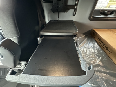Cab interior with a fold-out bunk/desk surface and a raised platform, showing a flat black tabletop and a side lip.
