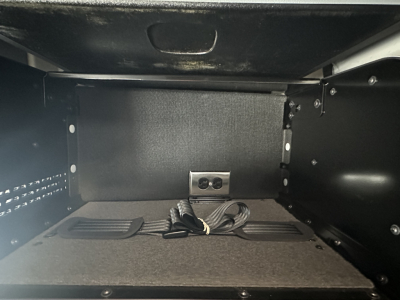Truck cab storage compartment with power outlet and corded plug visible in a Mack PR74TPR truck image.