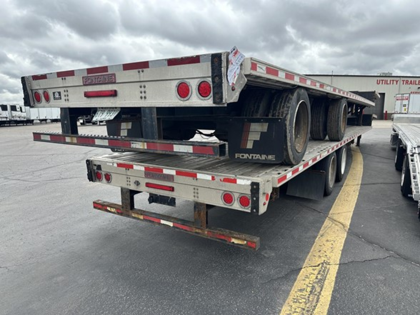 Trailer rear view of a Fontaine 53' combo drop deck with rear slide axle showing dual rear wheels and reflective tape.