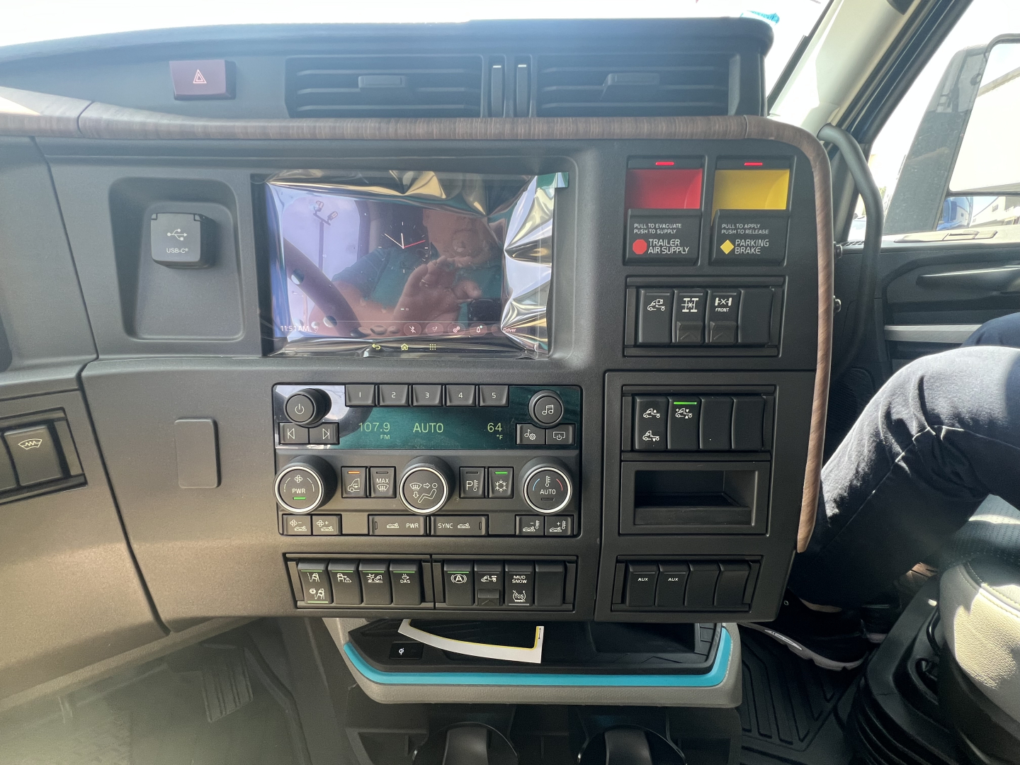 Volvo VNL dashboard view showing center console with touchscreen, climate controls, and various switches.