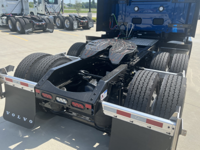 Volvo VNL64T860 tractor cab behind with fifth wheel and dual rear axles, view of chassis and suspension, trailer mudflaps with Volvo logo.