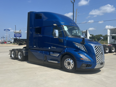 Volvo VNL64T860 truck in blue, side view showing chrome grille, aerodynamic sleeper cab, and multiple rear axles.