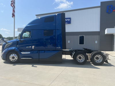 Volvo VNL64T860 truck tractor in blue side view showing aerodynamic cab and 6x4 drive configuration.