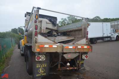 Dump truck bed with rear view showing plow mount and debris in bed, multiple tail lights, black mud flaps, and reflective tape.
