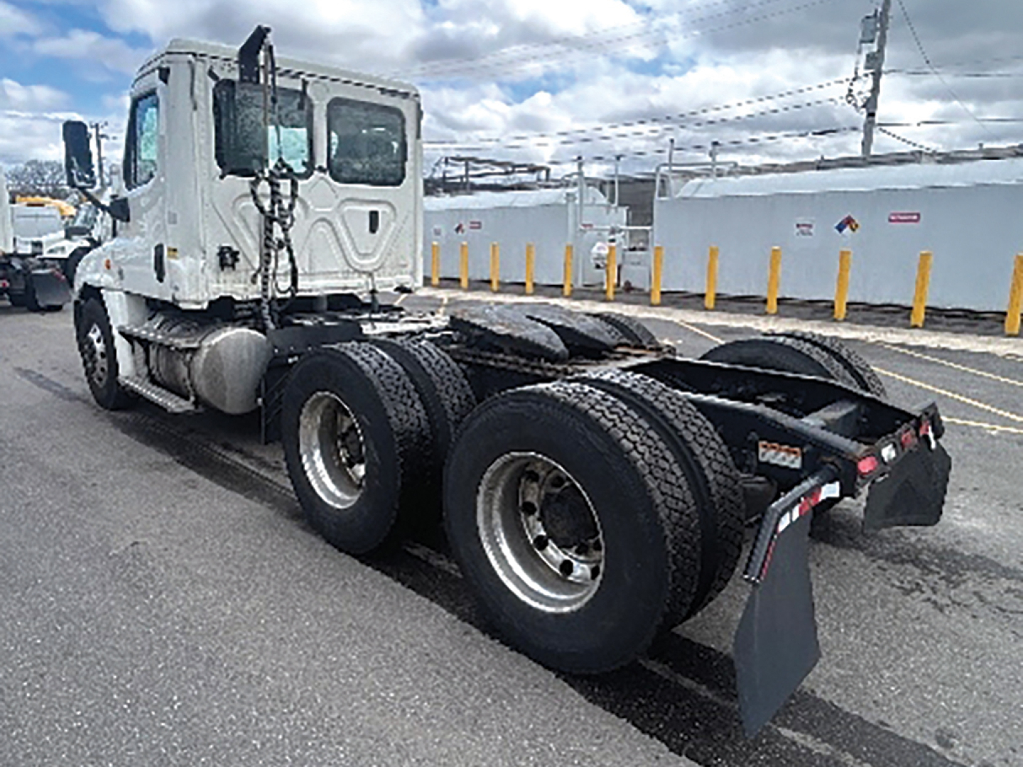 Freightliner Cascadia125 truck chassis with dual rear axles and lifted cab, show rear wheels and chassis.