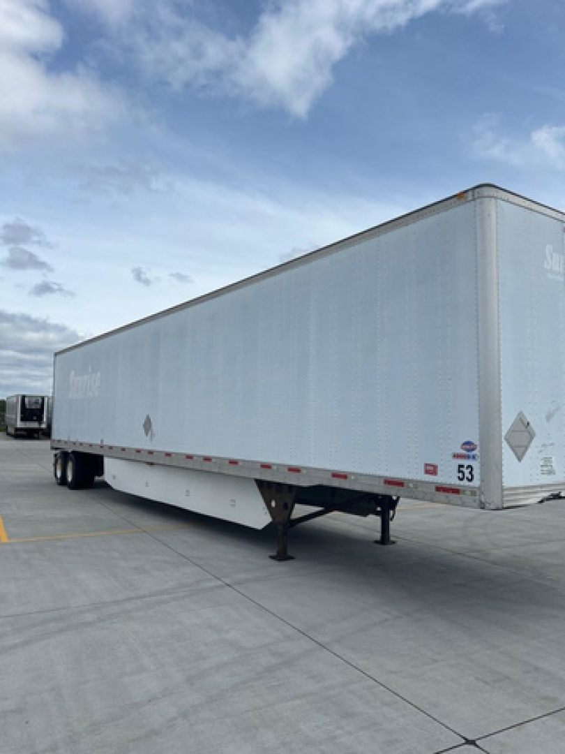 Semi trailer with a rectangular box, light gray exterior, parked in a lot; visible rear and support legs.